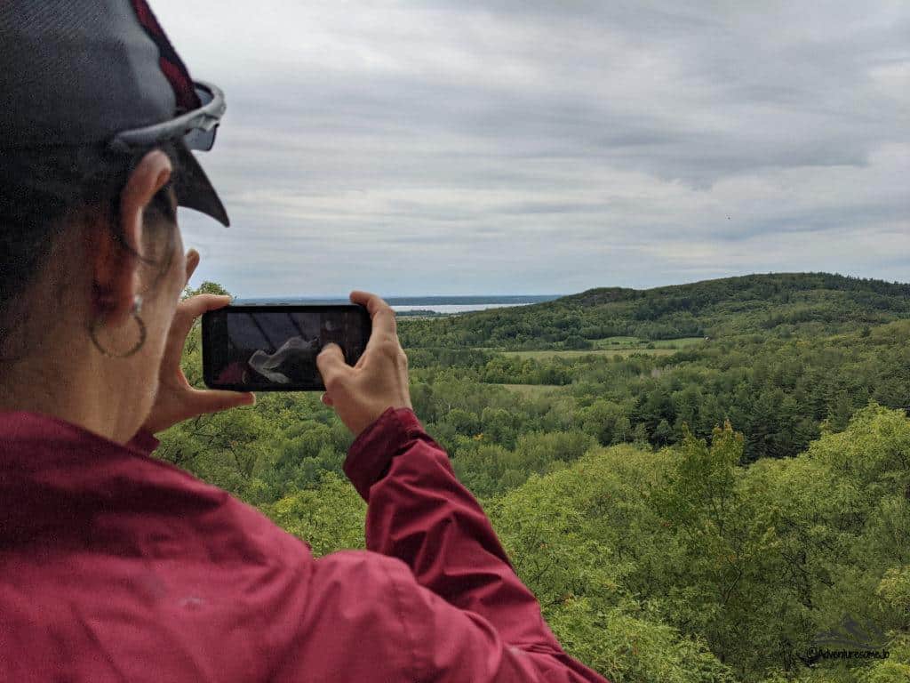 hiker taking a picture of the grassy and forested hills in landscape