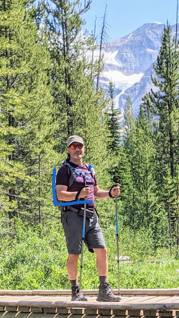 a hiker with his arm bent at 90 degree while holding his trekking poles