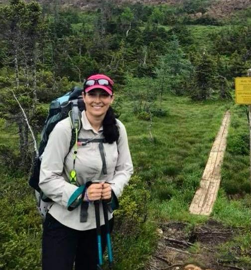 wearing light and loose clothing while backpacking on a grassy trail surrounded by conifers
