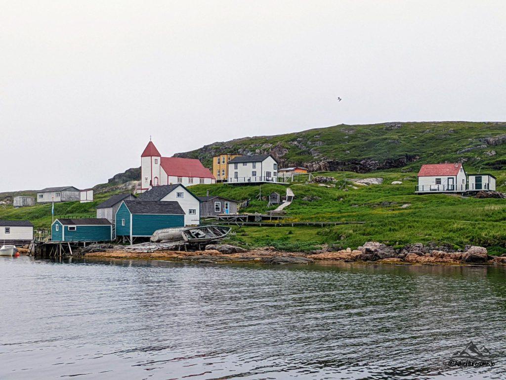 Battle Harbour as seen from the boat with the village's building and church on the grassy hill.