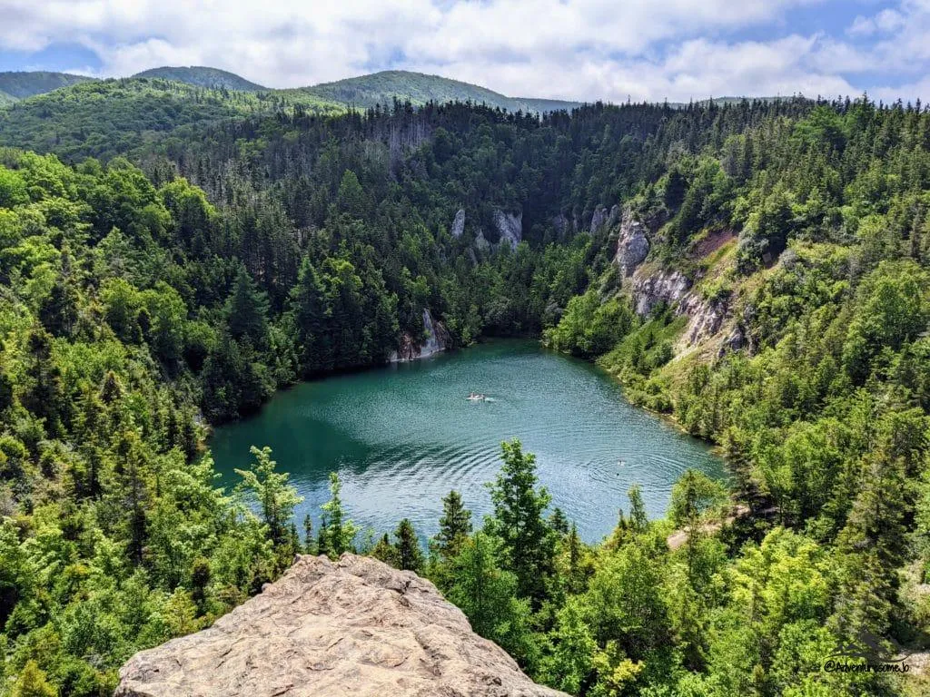 View of the lake's blue water in the Gypsum Mine surrounded by trees in Cheticamp Nova Scotia