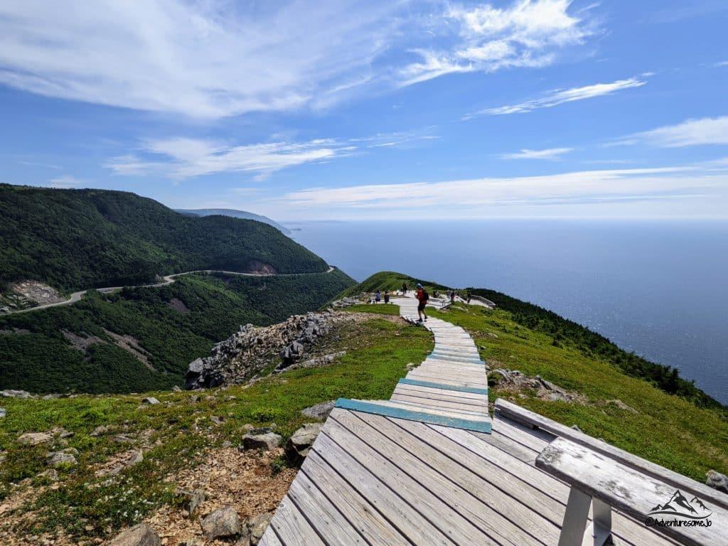 Randonneurs sur la promenade du sentier Skyline avec la piste Cabot errant dans les montagnes et les eaux bleues de la mer au loin