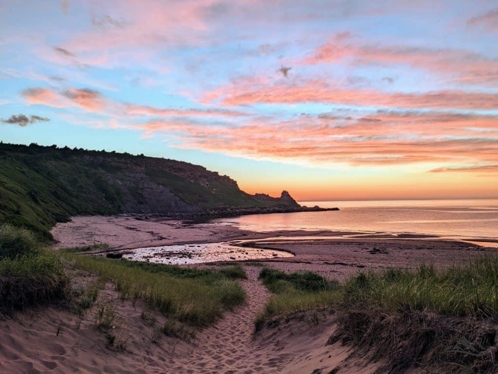 The evening sun and grassland, sands and ocean view of Chimney Cornor Beach in Cape Breton Island, Nova Scotia.