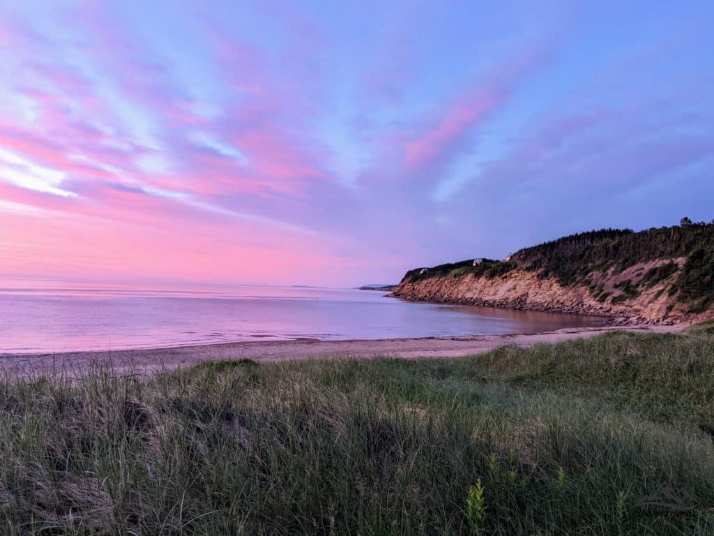 ciel rose et violet au-dessus de la mer sur une plage de sable en Nouvelle-Écosse