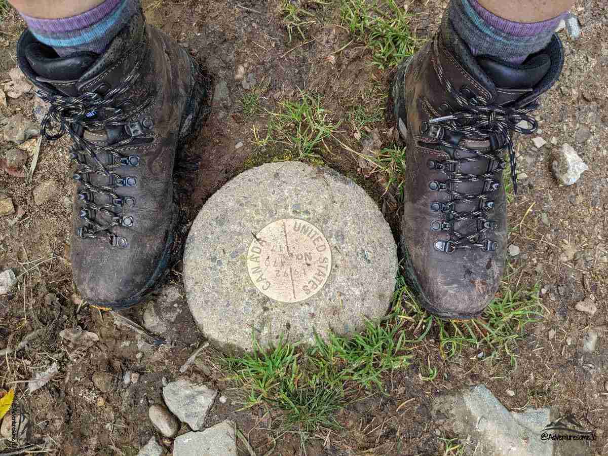 Standing over the border marker with one foot in Canada and one foot in the United States.