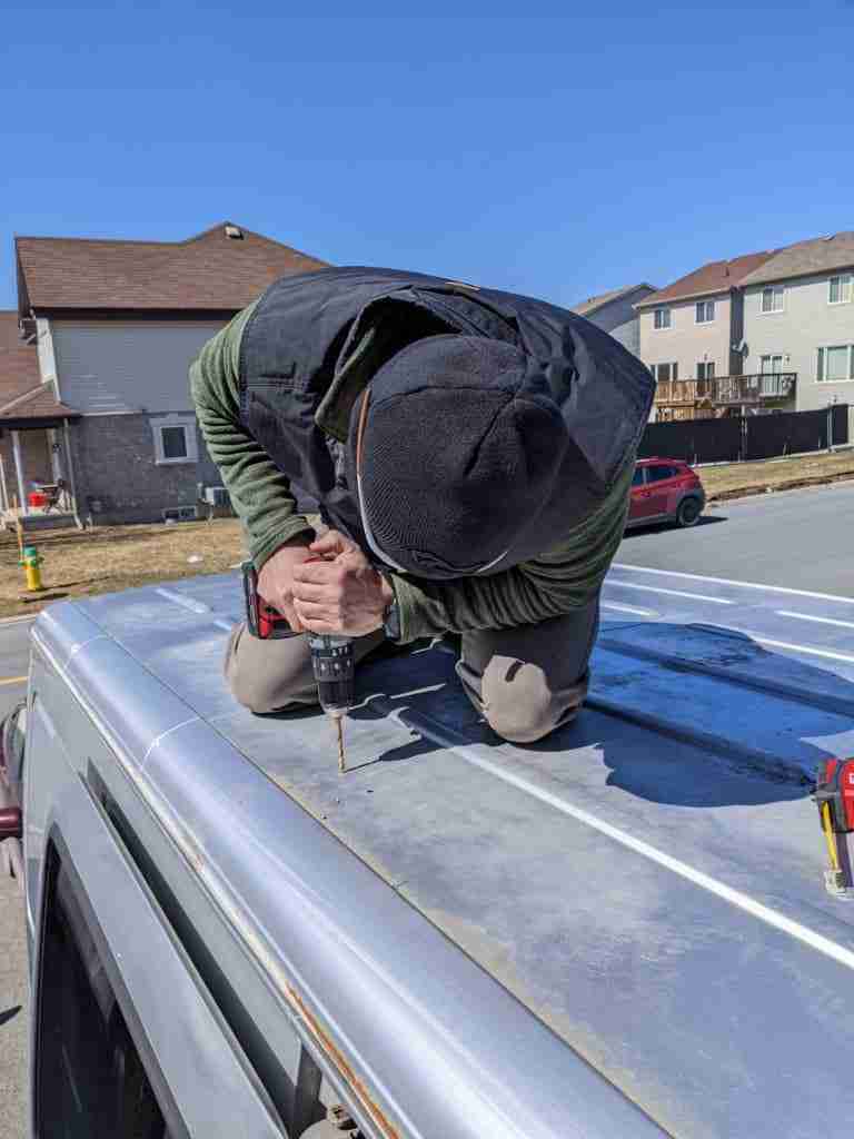 drilling wholes in the van roof to install solar panels for the solar system