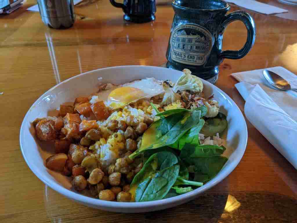 hearty breakfast bowl of chickpeas, quinoa and eggs with spinach with a cup of coffee