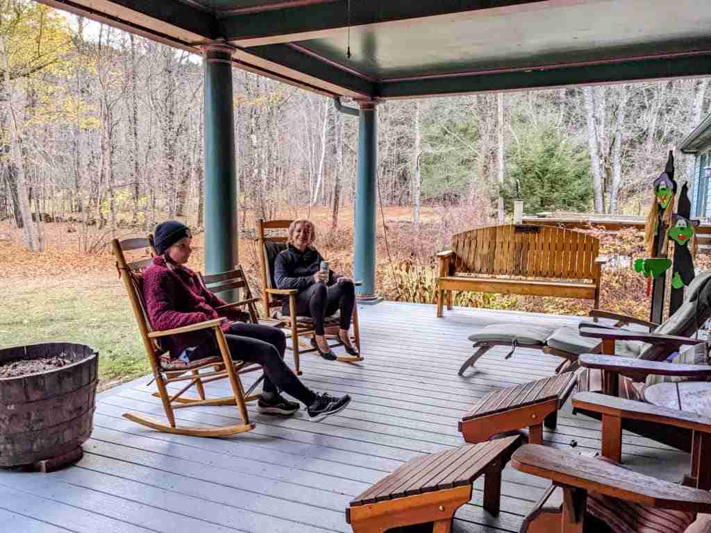 ladies sitting in rocking chairs on the porch enjoying the forest around them