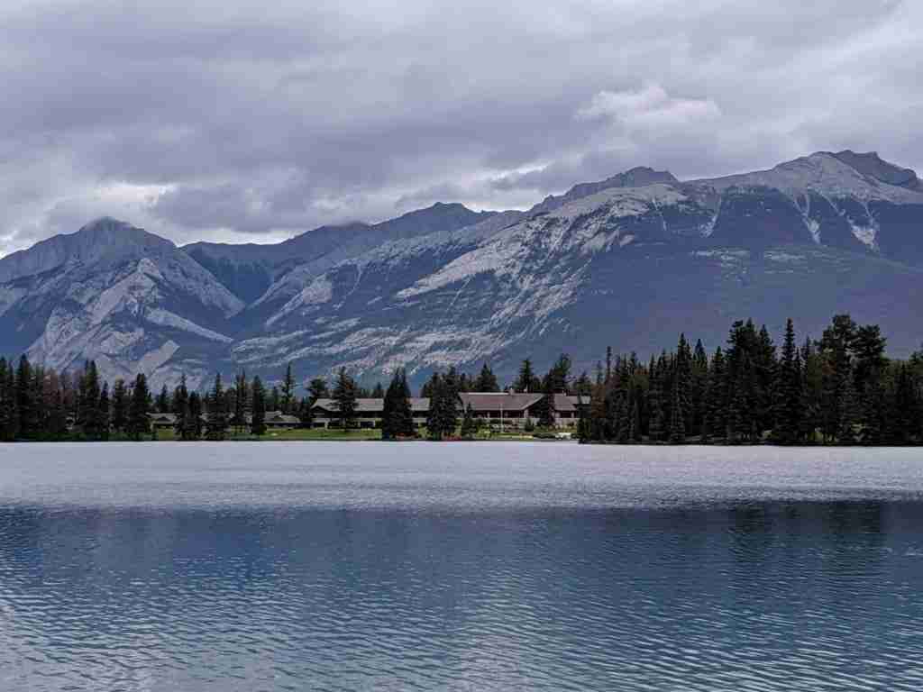 The Jasper Park Lodge across Lac Beauvert with the mountain range behind it in the Canadian Rockies