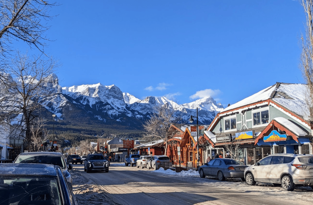 busy street in Canmore with the snowy mountains above the town