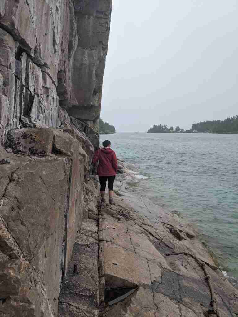 hiker by the rock walls hiking along Lake Superior