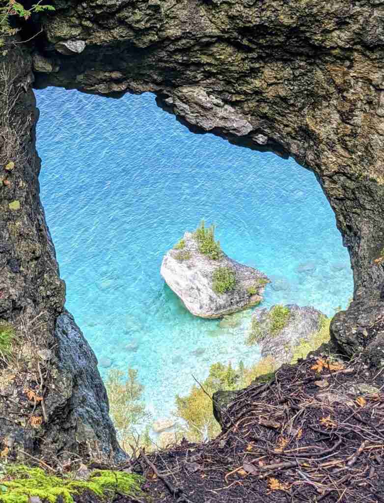 Small island seen from a whole on the cliff side on Lion's Head hiking trail