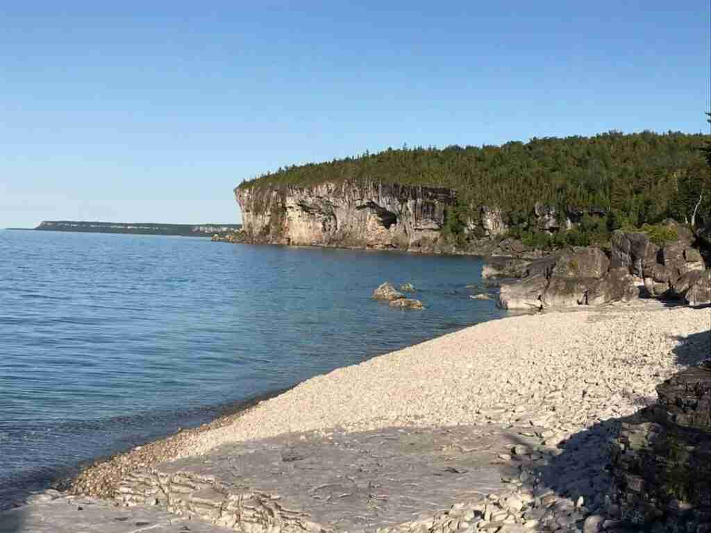 Rocky beach on Georgian bay with the cliffs in the distance over calm water