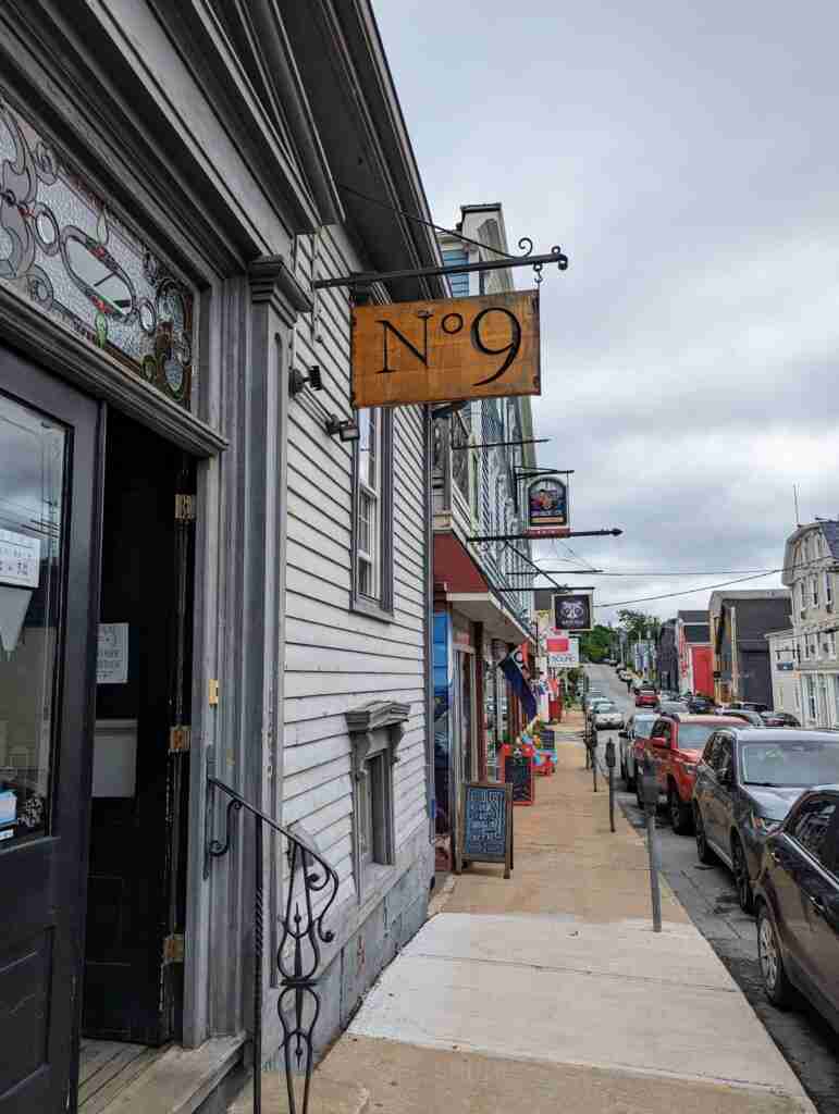 the Montague Street sidewalk in Lunenburg Nova Scotia with the N.9 Cafe sign hanging above the door