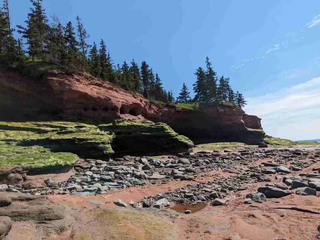 le fond de l'océan à marée basse avec le sable rougeâtre, les rochers éparpillés et la formation rocheuse de grès habituelle dans le parc provincial Burntcoat Head