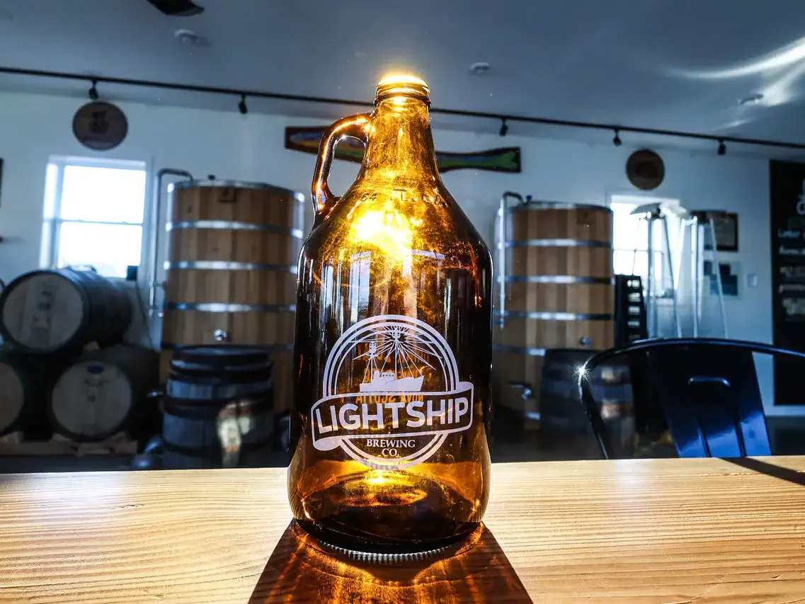 Lightship Brewery beer bottle set on a wodded table with the beer wooded barrels in the background