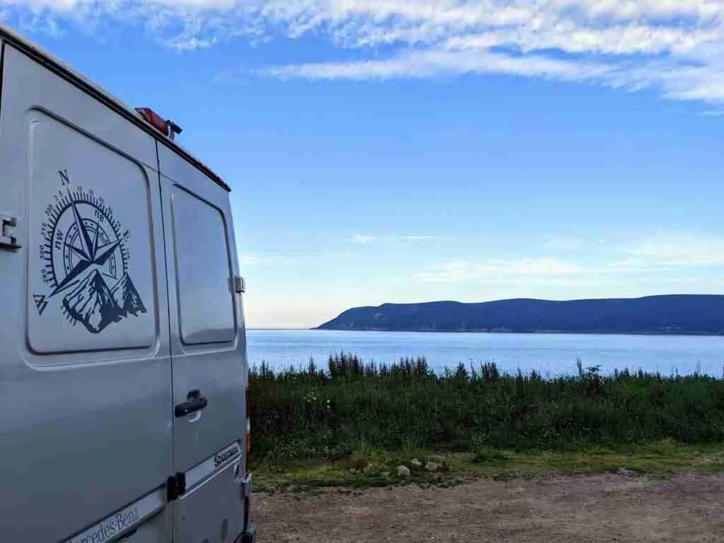 fourgonnette garé au bord de l'eau avec les collines de l'autre côté de la baie
