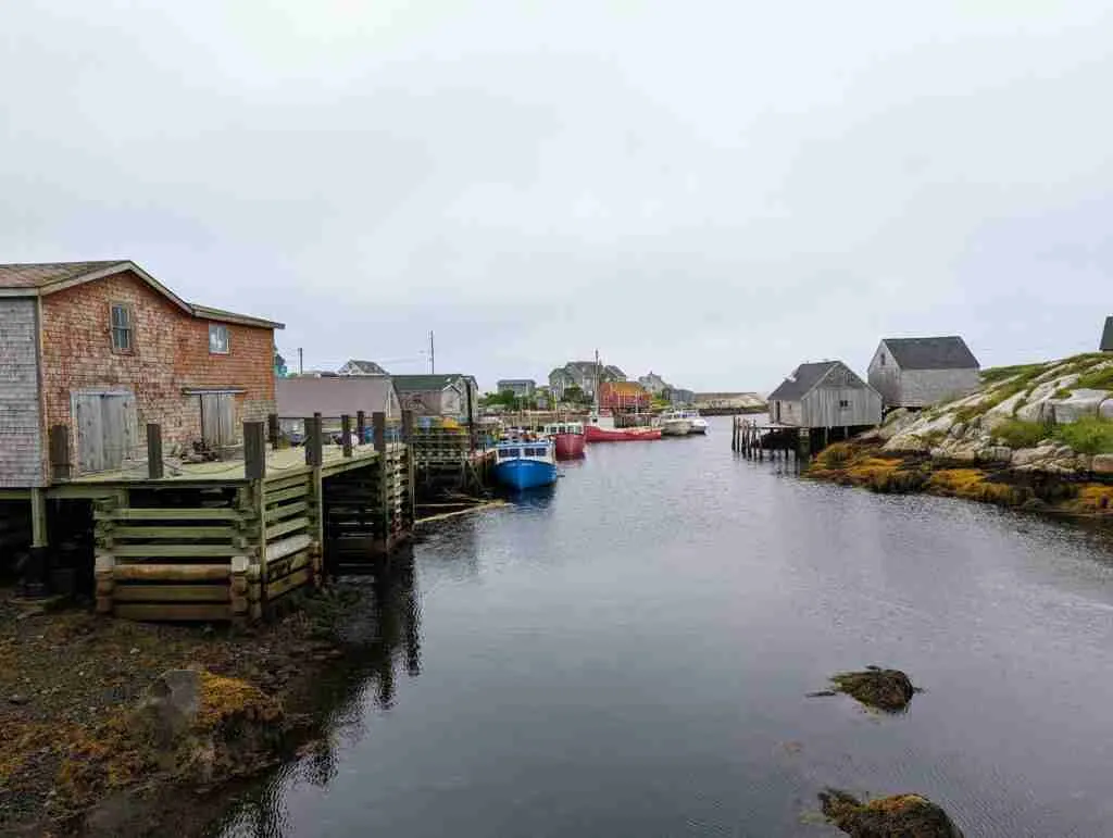 Village de pêcheurs de Peggy's Cove avec les cabanes de pêcheurs le long du port et les bateaux de pêche amarrés par une journée grise.