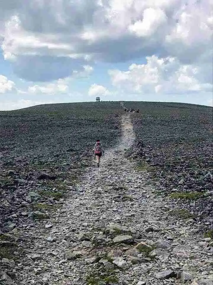 un randonneur marchant vers le sommet le long du sentier couvert d'éboulis