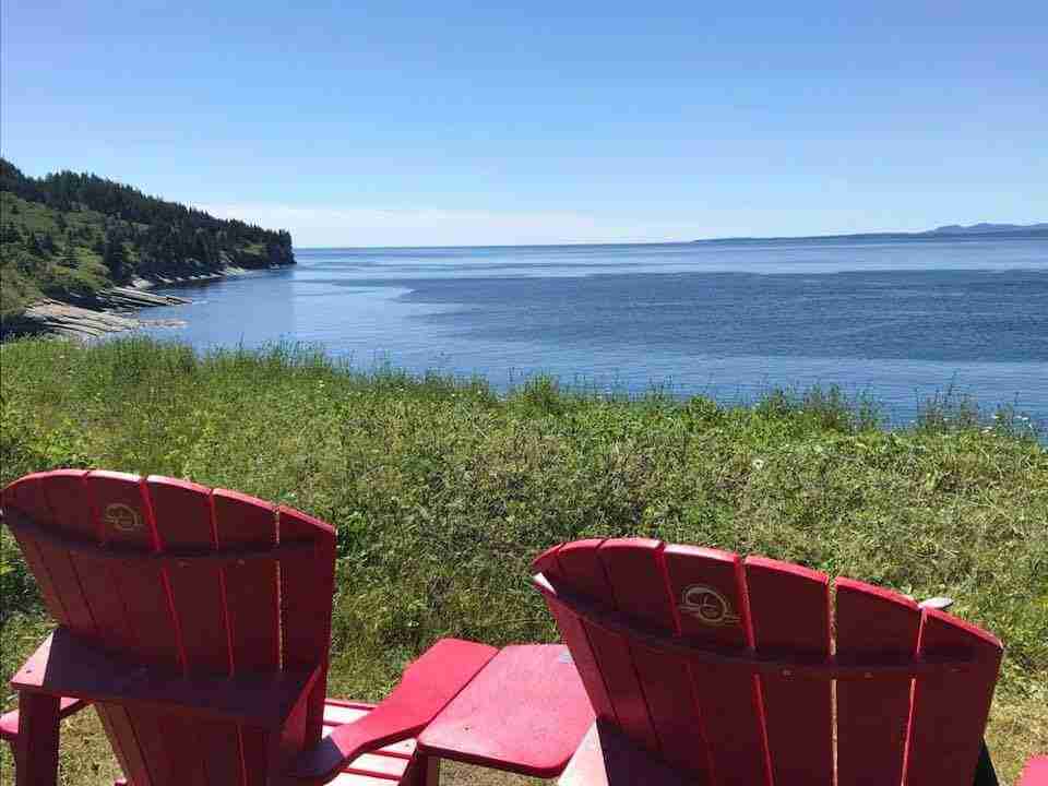 Chaises rouges de Parcs Canada avec vue sur la mer dans la baie de Gaspé