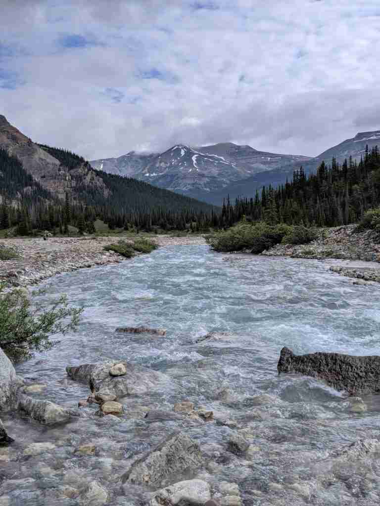 hiking by the river in the valley surrounded by mountains