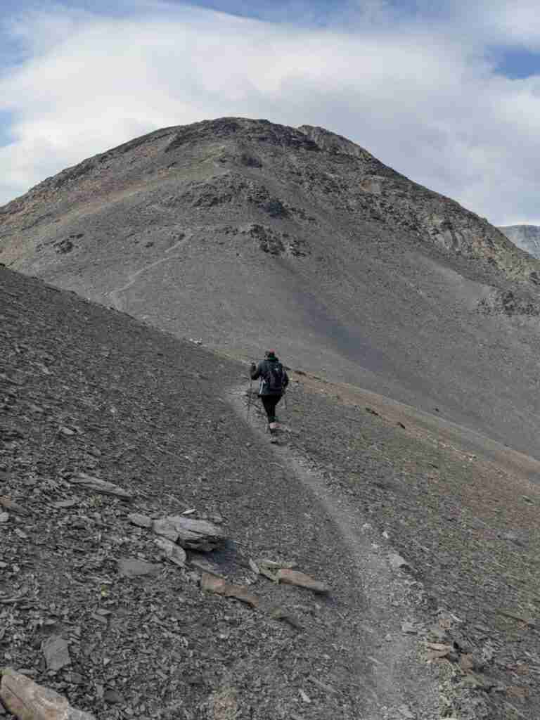 woman hiking on rocky trail going up a mountain with no vegetation