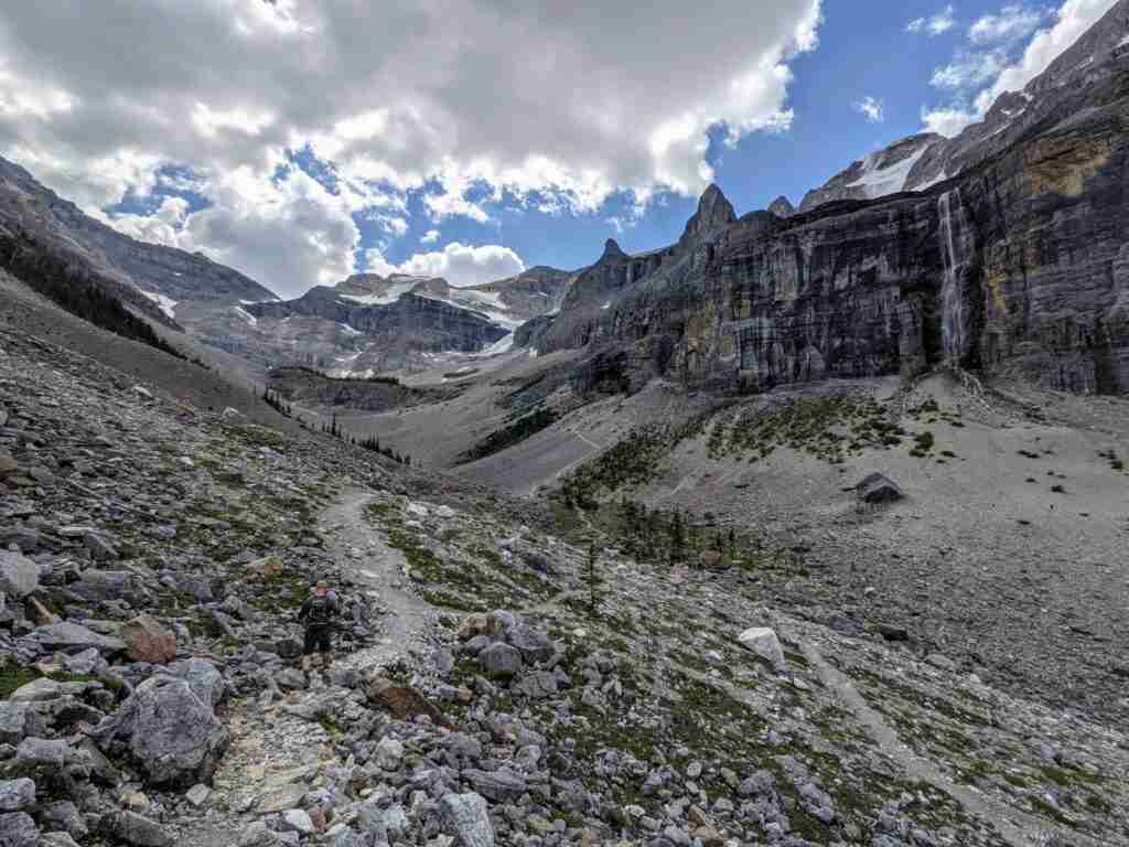 Hiker on a worn path in the scree heading towards the valley and the Stanley Glacier