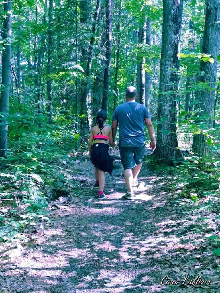 a man and a child walking on a trail in forest