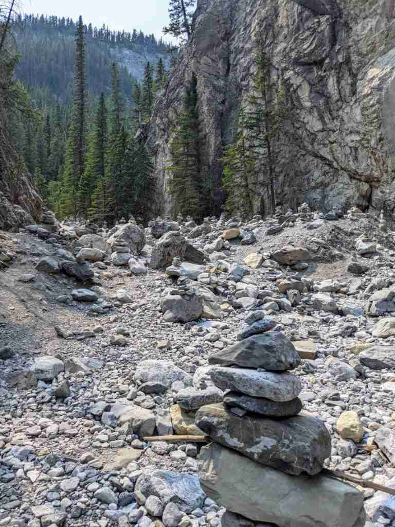 Des Inukshuks dispersés partout dans le lit rocheux du ruisseau lors de la randonnée Grotto Canyon