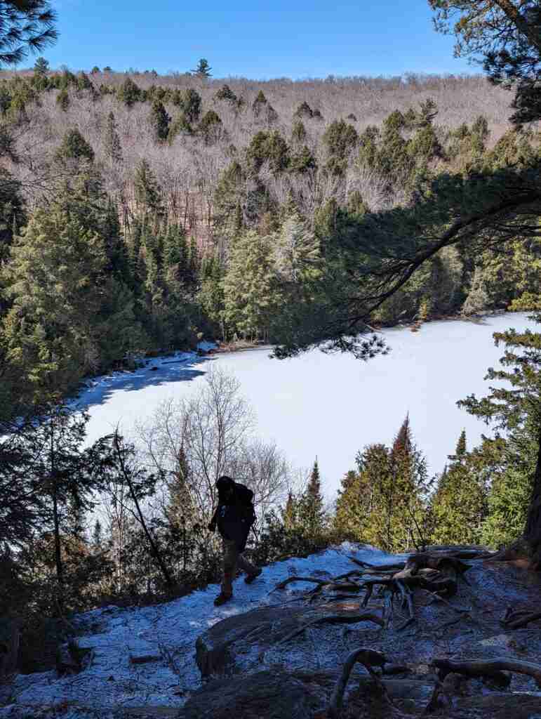 Hiker on the snowy trail above a frozen lake in Algonquin Park