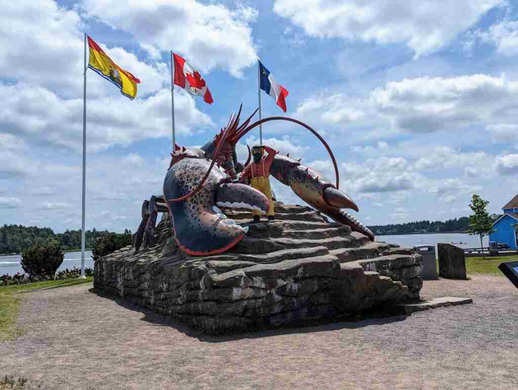 Giant Lobster in Shediac with the three flags flying in the wind behind it; New Brunswick, Canada and Acadie.