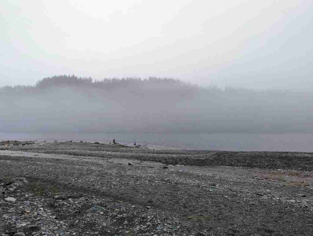 Point Wolf rocky beach with hills on the far shore hidden behind fog