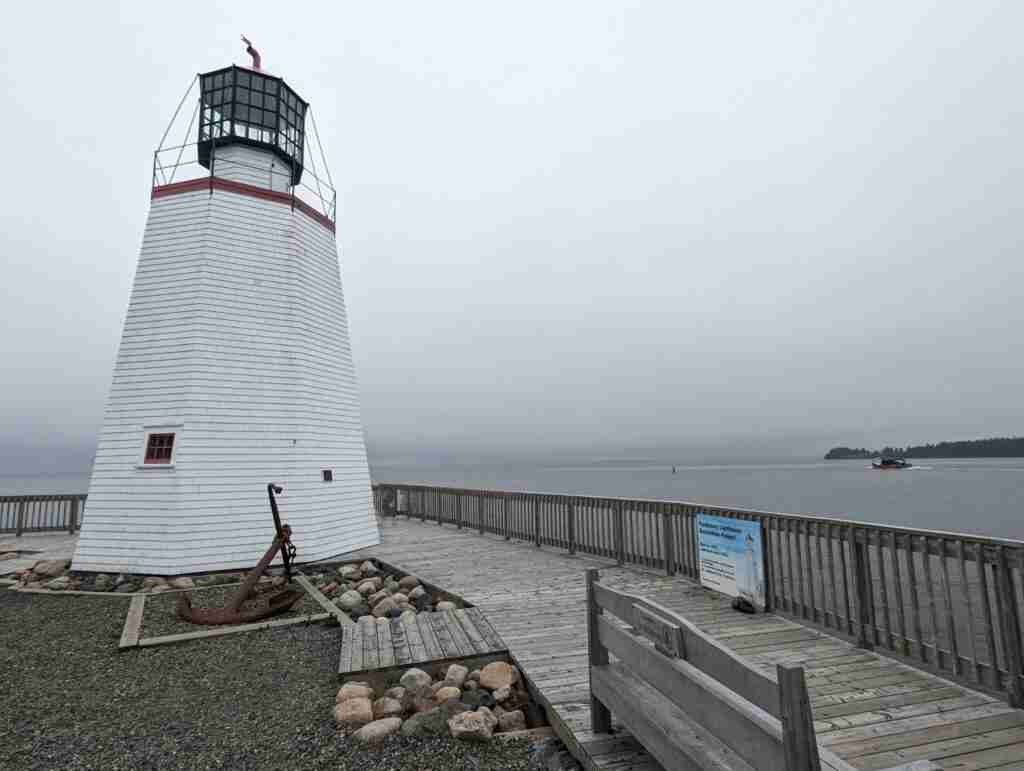 white lighthouse surrounded by boardwalk and view of the sea