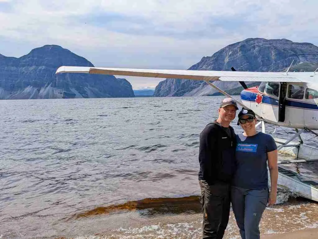 a couple posing in front of float plane on Doctor Lake during a plane tour of Nahanni National Park
