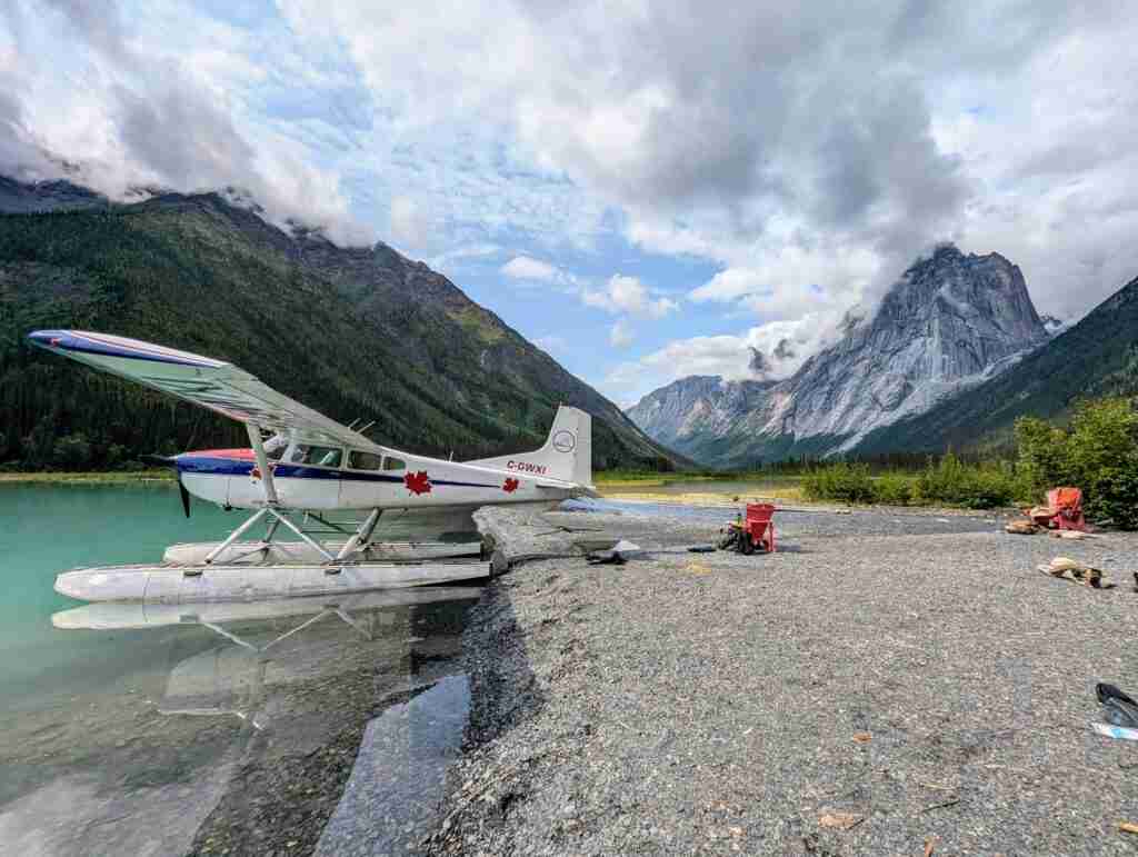 floatplane on the shore of a clear blue lake surounded by mountains in Nahanni National Park