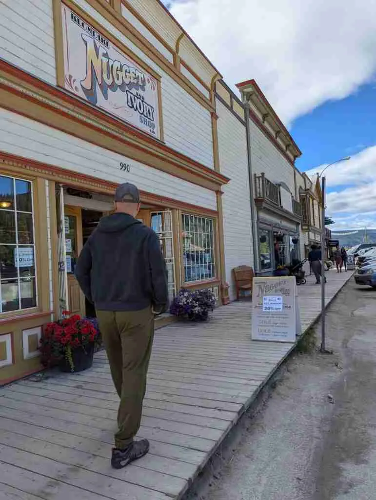 un touriste se balade sur les promenades de la rue principale avec de vieux bâtiments de style western à Dawson City, au Yukon