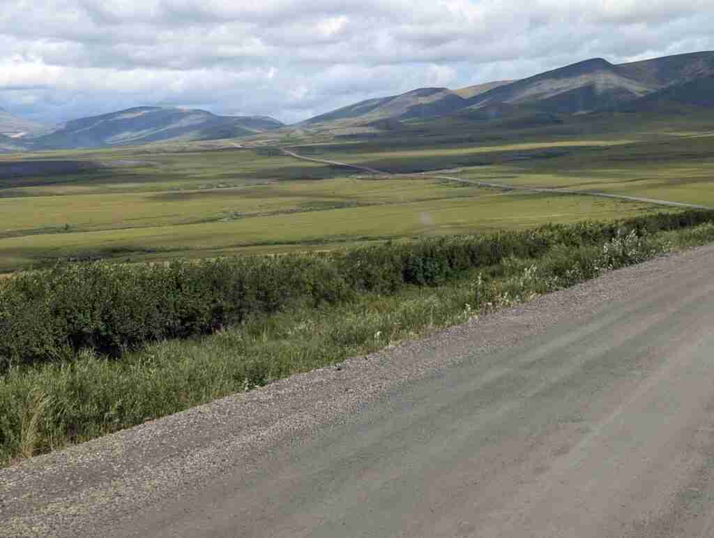 gravel road of Dempster Highway through plains and rolling hills