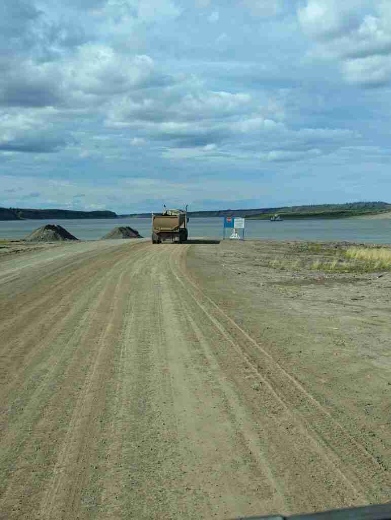 dirt road coming to en end in a river with a truck waiting for the ferry