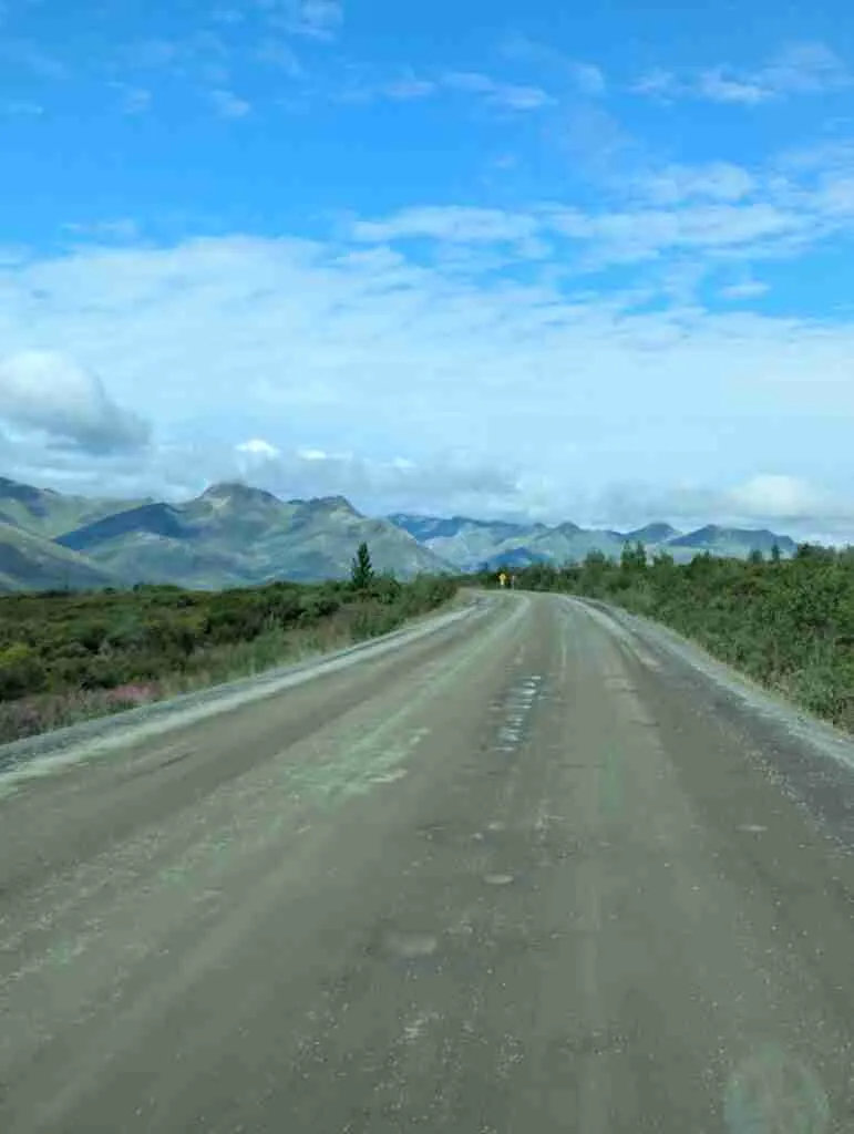 The dirt road with potholes of the Dempster Highway with Tombstone Mountains in the distance