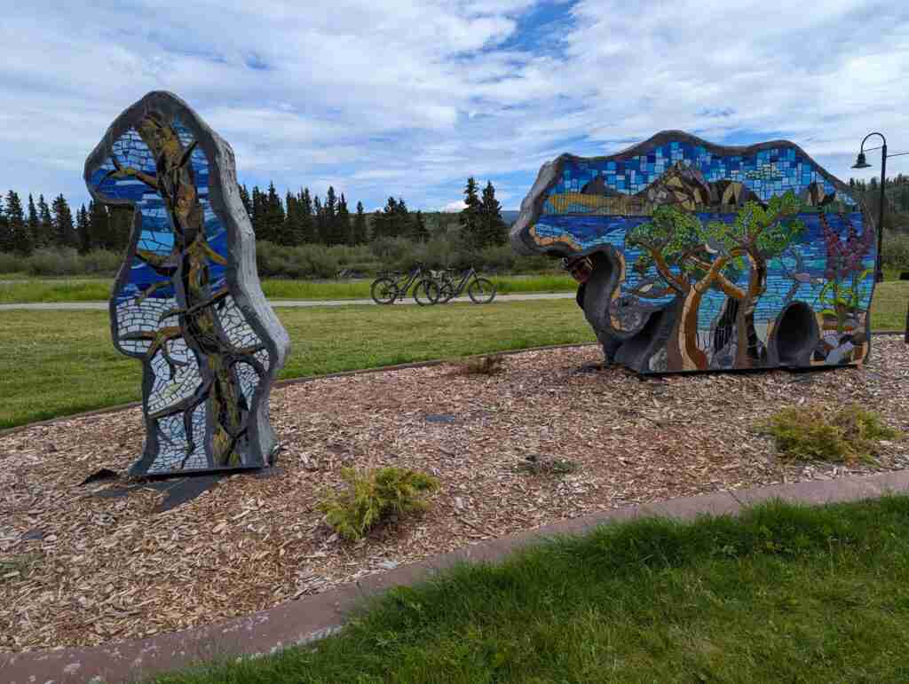 deux statues en forme d'ours avec des arts représentant la nature sur leurs corps près de la piste cyclable à Whitehorse, au Yukon