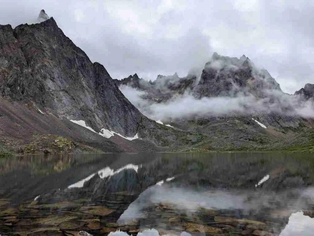 Grizzly Lake surrounded by mountains with clouds hanging low