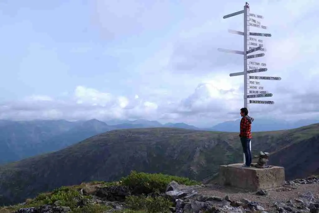 Randonneur debout à côté du panneau au sommet de Keno Hill à Keno City, Yukon