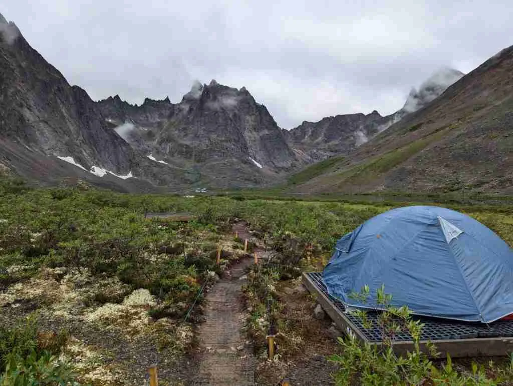 tent on a plateform in a valley surrounded by tall mountains