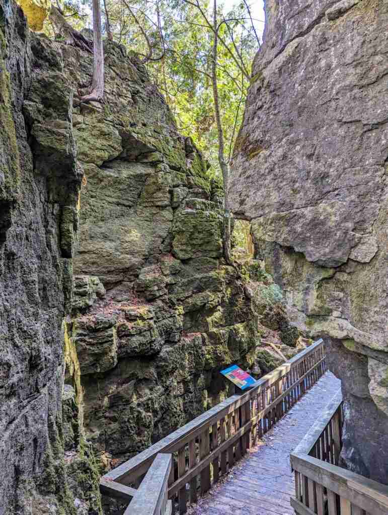 boardwalk with tall rock walls on each side in Mono Cliffs Provincial Park in Ontario