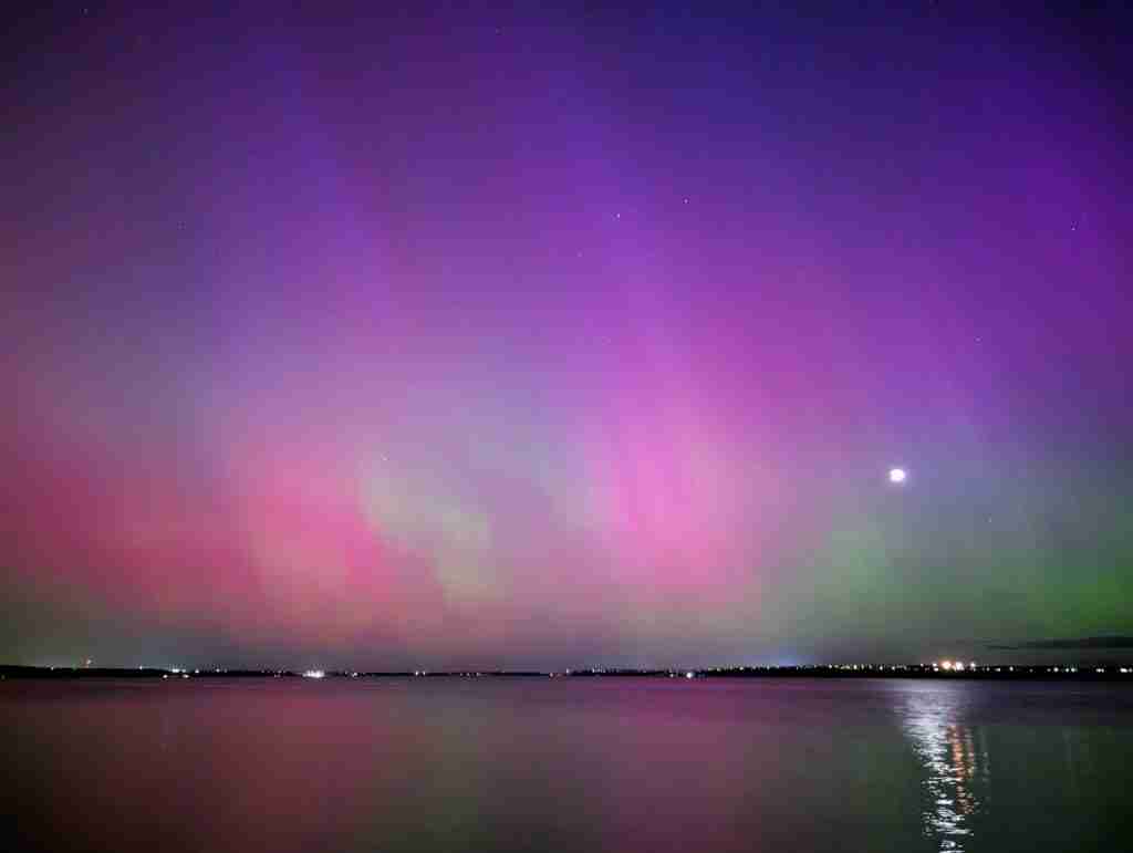 aurores boréales vertes et violettes dansent au dessus d'un lac au Canada