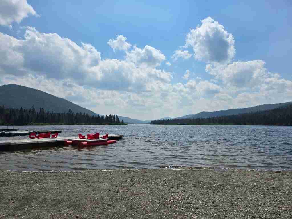 plage de galet au bord du lac Cascapédia entouré de conifères avec les montagnes derrière