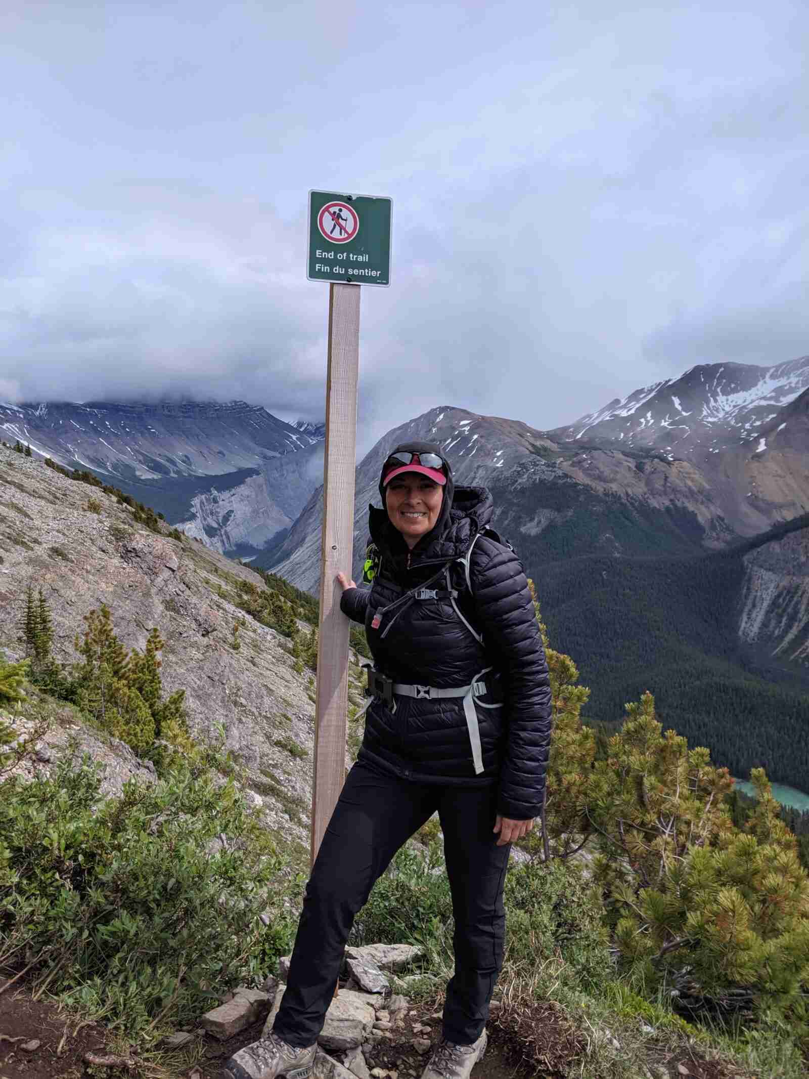 hiker beside the End of the Trail sign on the Parker Ridge Hike