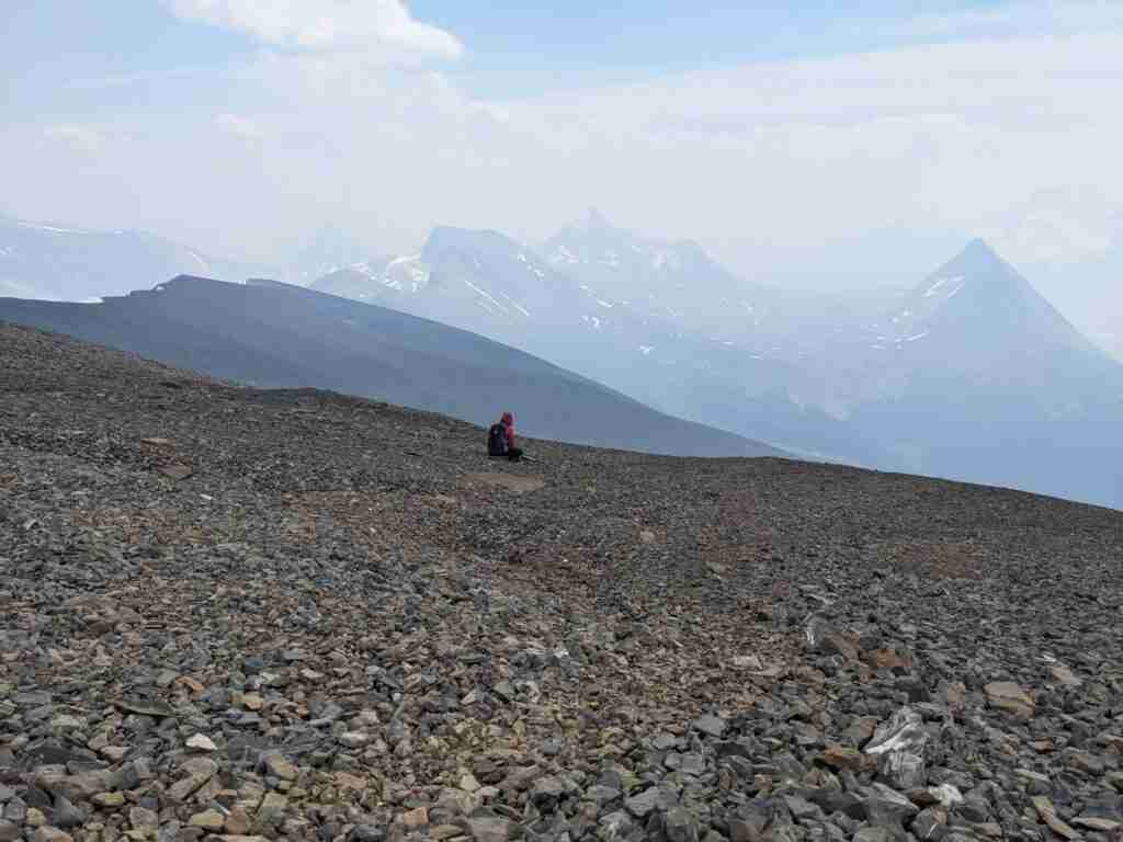 Hiker taking a break sitting on scree on Tangle Ridge
